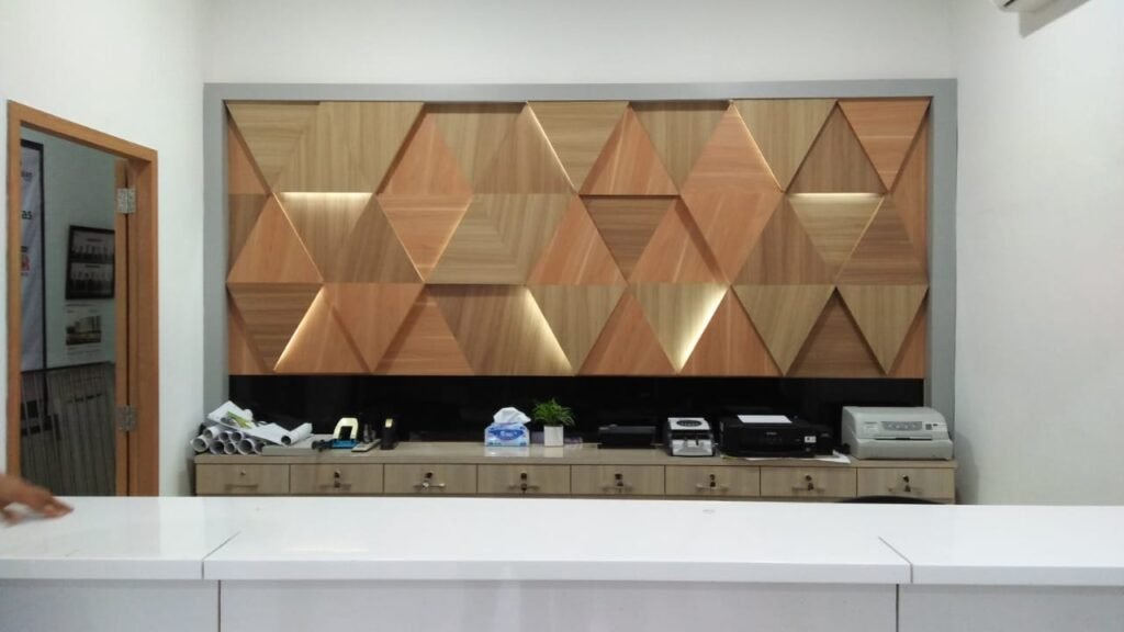 Backdrop panel motif kayu segitiga dengan lampu LED di belakang loket Pegadaian Cabang Sei Panas