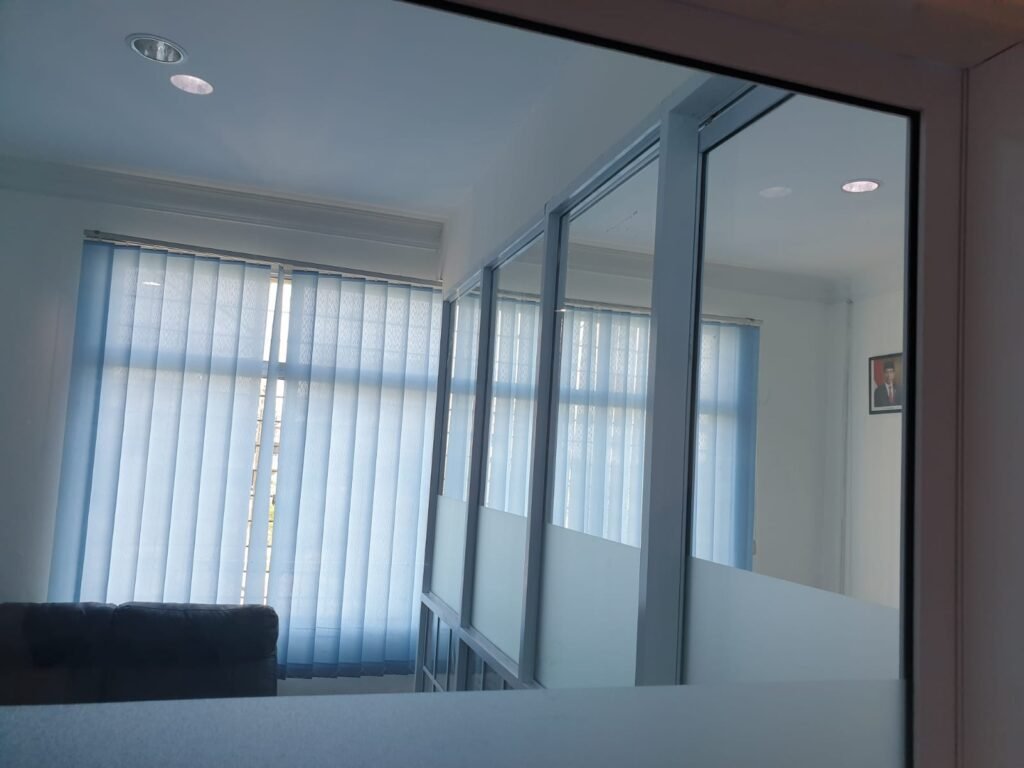 Ruang kerja dengan partisi kaca dan vertical blind di kantor Pegadaian Cabang Sei Panas Batam